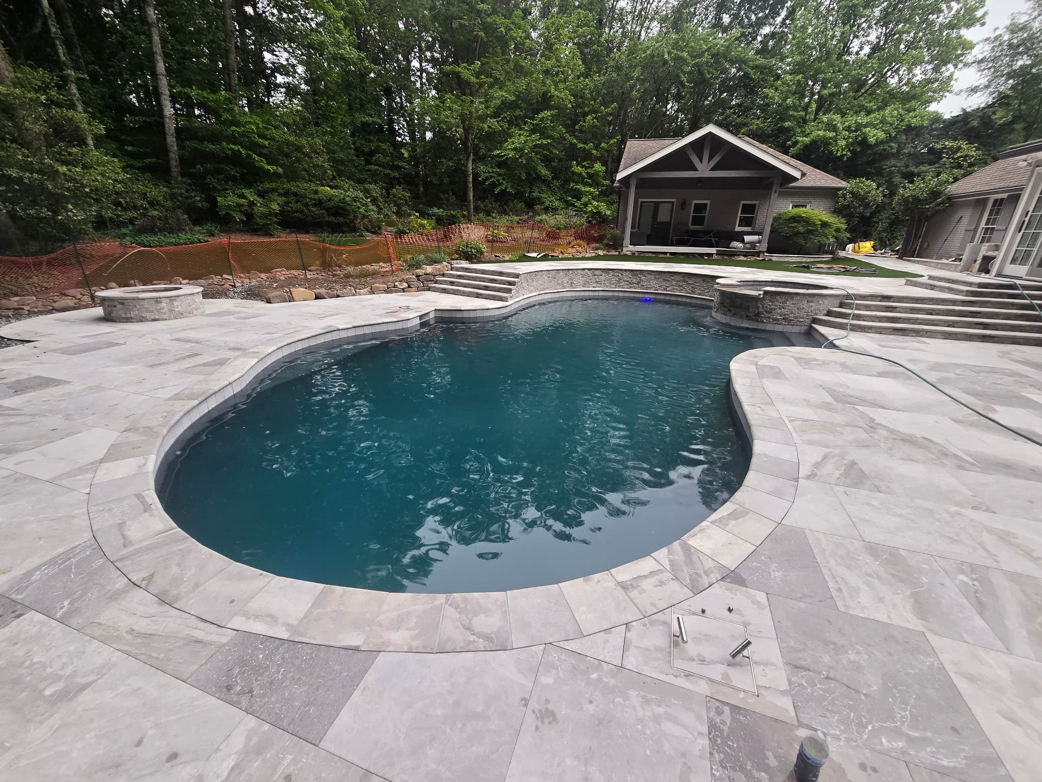 Completed freeform pool with stone veneer raised spa and multi-level deck
