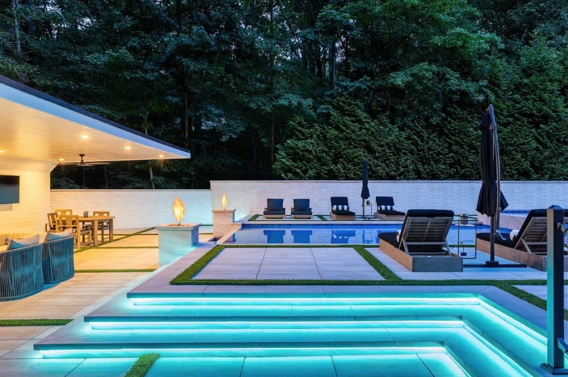 Twilight view of the Buckhead pool, illuminated spa steps, covered pavilion, and wooded backdrop