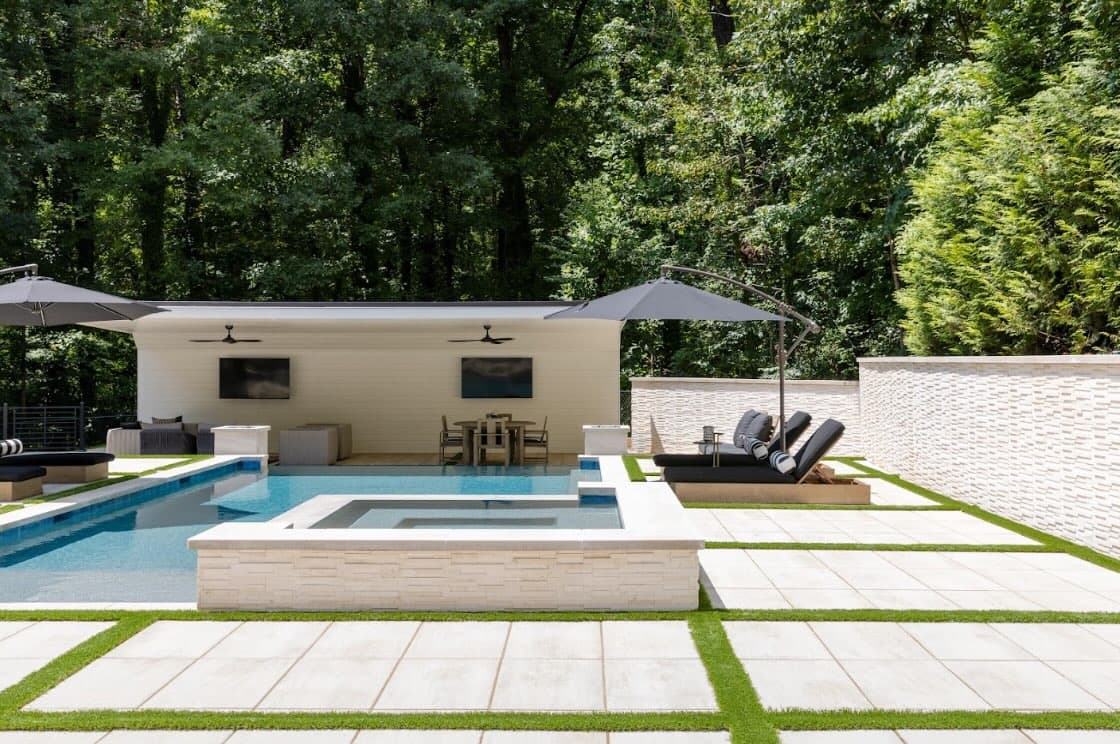 Daylight view of the Buckhead pool and raised spa framed by pale stone and turf accents